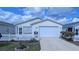 Inviting single-story home featuring a well-manicured lawn, white picket fence, and an attached garage at 3449 Roanoke St, The Villages, FL 32162