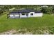 Aerial view of a bright, white single-story home with a covered patio and a large green lawn at 42157 Tamarac St, Eustis, FL 32736