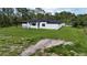 Aerial view of a bright, white single-story home with a covered patio and a large green lawn at 42157 Tamarac St, Eustis, FL 32736