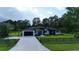 Stunning single-story home featuring a modern black and white exterior, lush lawn, and palm tree accents at 42157 Tamarac St, Eustis, FL 32736