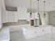 Bright kitchen boasts white cabinets, quartz countertops, an island and modern pendant lighting at 42200 Chinaberry St, Eustis, FL 32736