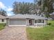 House exterior featuring stone accents, a screened garage, and a landscaped yard at 5004 Saint Andrews Arc, Leesburg, FL 34748