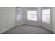 Bright bedroom with gray carpet and three windows with blinds at 5622 King James Ave, Leesburg, FL 34748