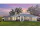 Tan house with gray roof, white trim, and landscaping; dusk photo at 5622 King James Ave, Leesburg, FL 34748