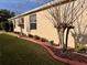Home exterior showcasing meticulous landscaping including decorative brick edging, green lawn, trimmed shrubs and young Crape Myrtle trees at 752 Maybank Loop, The Villages, FL 32162