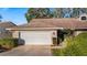 Inviting exterior of a single-story home with a two-car garage and manicured landscaping at 8801 Village Green Blvd, Clermont, FL 34711