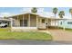 Charming single-story home with a screened-in porch, carport, manicured lawn, and palm trees at 12 Hilly Way, Fruitland Park, FL 34731