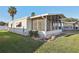 Exterior view of a well-kept mobile home with a screened-in porch and landscaped yard, perfect for relaxed living at 12 Hilly Way, Fruitland Park, FL 34731