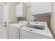 Convenient laundry room equipped with a washer, dryer, and storage cabinets at 17350 Se 116Th Court Rd, Summerfield, FL 34491