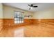 Inviting bedroom featuring wood floors, wood paneling, ceiling fan, and a window at 18033 Rose St, Groveland, FL 34736