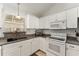 Corner kitchen with white cabinets, granite countertops, a modern electric range and stainless steel sink at 1904 De Hoyos Pl, The Villages, FL 32159