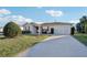 Tan house with red shutters, attached garage and a well-kept lawn at 2486 Five Forks Trl, The Villages, FL 32162