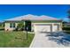 Single-story house with light green exterior, two-car garage, and landscaped yard at 25619 Maurepas Ln, Leesburg, FL 34748