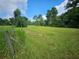 Vacant lot with grassy field, trees, and a wooden fence at 3180 Sixma Rd, Lake Helen, FL 32744