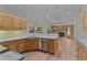 Open kitchen with wooden cabinets, stainless steel appliances, and view into the brick fireplace at 35534 Quail Run, Leesburg, FL 34788