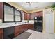 Kitchen features dark wood cabinets, granite countertops, and black appliances at 3839 Manor Oaks Ct, Leesburg, FL 34748