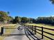 Ornate iron gate opens to a long driveway, leading to a private estate with fenced pastures at 43140 Hossin Around Ln, Altoona, FL 32702