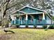 Teal home with a wrap-around porch and peacocks on the lawn at 43140 Hossin Around Ln, Altoona, FL 32702