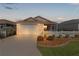 Tan house with white picket fence, two-car garage, and screened porch at dusk at 1387 Zest Ave, The Villages, FL 32163