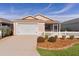 Tan house with white picket fence, two car garage, and screened porch at 1387 Zest Ave, The Villages, FL 32163