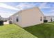 Rear view of tan house with grassy yard and AC unit at 1387 Zest Ave, The Villages, FL 32163
