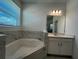This spacious bathroom features a soaking tub with marble surround, a vanity, and a window with blinds at 2137 Sunshine Peak Dr, Minneola, FL 34715