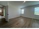 A bright bedroom with wood-look flooring, windows with blinds, and an open doorway to a kitchen at 2137 Sunshine Peak Dr, Minneola, FL 34715
