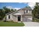 Two-story house with gray siding, light-colored garage doors, and landscaping at 2252 Juniper Berry Dr, Minneola, FL 34715
