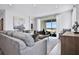 Spacious living room with gray sectional sofa, large windows, and hardwood floors at 2252 Juniper Berry Dr, Minneola, FL 34715