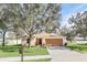 Tan house with brown garage door and a mailbox; large tree in front at 2717 Breezy Meadow Rd, Apopka, FL 32712