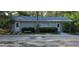 View of detached structure with gray siding, white doors, small trees and bushes surrounding at 2937 Eagles Nest Rd, Fruitland Park, FL 34731