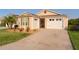 Tan house with white garage door, landscaping, and palm trees at 5415 Zajac Ave, The Villages, FL 32163