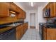 Traditional kitchen with wood cabinets, black countertops, and tile flooring at 6100 Windmill Rd, Leesburg, FL 34748
