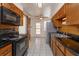 Kitchen featuring wood cabinets, black appliances, and white tile flooring at 6100 Windmill Rd, Leesburg, FL 34748