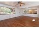 Bright living room featuring laminate wood flooring, white walls, large windows, and a ceiling fan at 6100 Windmill Rd, Leesburg, FL 34748