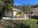 Two-story house with light-colored siding, palm trees, and a well-maintained lawn at 9001 Village Green Blvd, Clermont, FL 34711