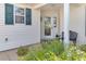 Front entrance with a glass door, black bench, and lush greenery at 906 Drakeswood Ave, The Villages, FL 32162