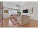 Living room with hardwood floors, beige sofas, and a large TV at 906 Drakeswood Ave, The Villages, FL 32162