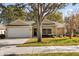 Tan one-story house with a white garage door and landscaping at 979 Princeton Dr, Clermont, FL 34711