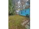 Small backyard with light brown grass and a teal mobile home at 1005 Oakland St. St, Tavares, FL 32778