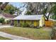 Yellow house with metal roof, screened porch, and yard at 1319 Stowe Ave, Mount Dora, FL 32757