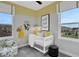 Bedroom with crib, armchair, and yellow and grey color scheme at 13243 Peaceful Melody Dr, Winter Garden, FL 34787