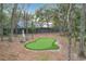 Backyard putting green surrounded by mature trees and natural landscaping at 1701 Cedar Stone Ct, Lake Mary, FL 32746