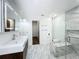 Bathroom featuring glass shower, marble floors and walls, floating vanity, and illuminated mirrored medicine cabinet at 1701 Cedar Stone Ct, Lake Mary, FL 32746
