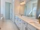 Double vanity bathroom with quartz countertop and large mirror at 2022 Wallingford Loop, Mount Dora, FL 32757