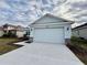 House exterior featuring a light blue color scheme, a two-car garage, and a stone facade at 2046 Wallingford Loop, Mount Dora, FL 32757