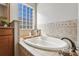 Relaxing bathroom with soaking tub, tile surround, and a large window at 2054 Vision Ct, The Villages, FL 32163