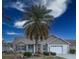 Tan house with palm tree, landscaping, and a two-car garage at 2219 Welcome Way, The Villages, FL 32162