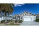 Tan house with palm tree, landscaping, and a two-car garage at 2219 Welcome Way, The Villages, FL 32162