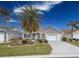 Tan house with palm trees, landscaping, and a two-car garage at 2219 Welcome Way, The Villages, FL 32162